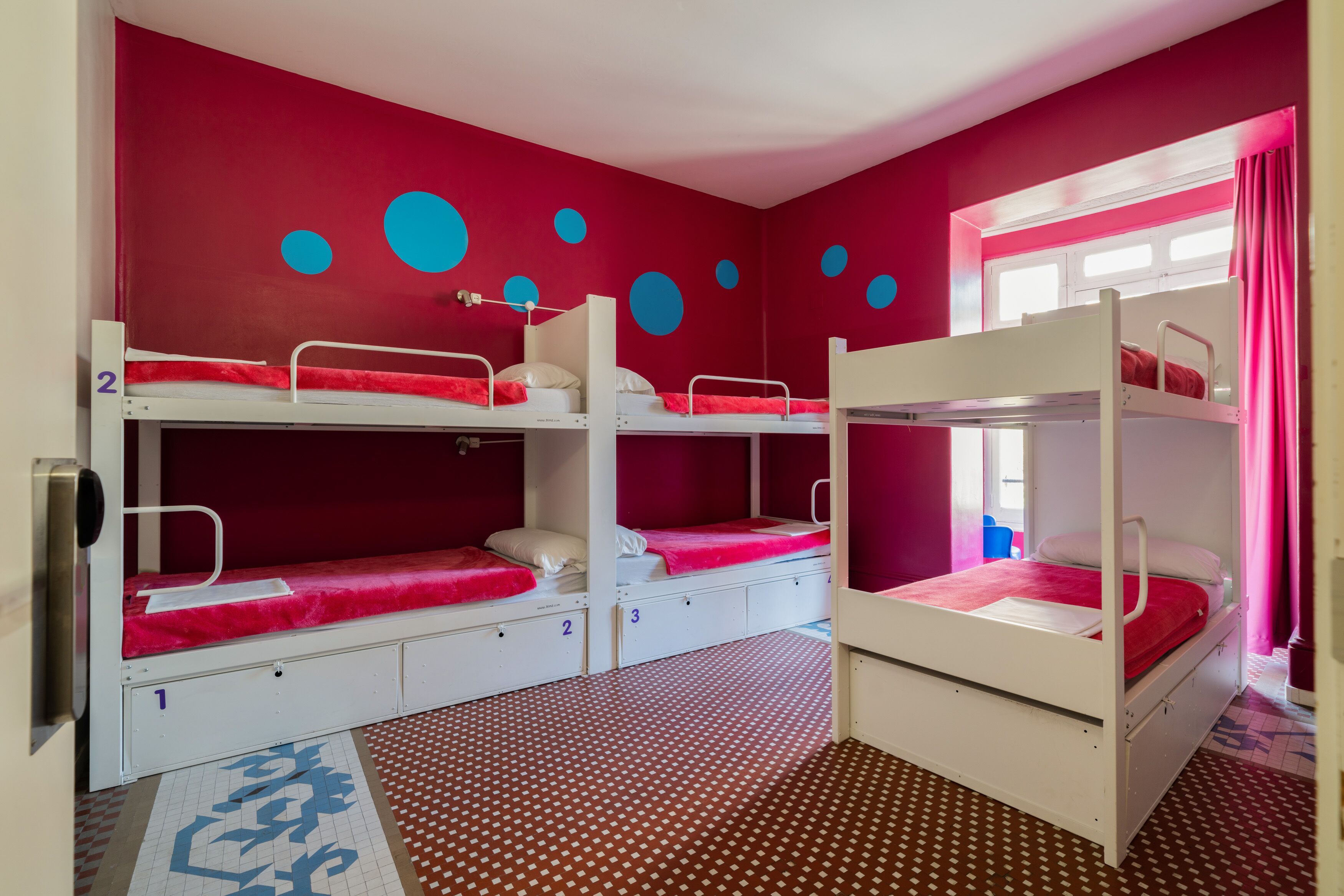Un dormitorio con literas, cajones numerados para guardar pertenencias y un suelo con estampado.