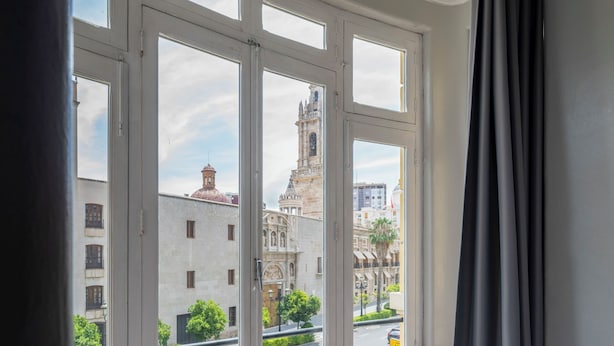 A room with a large window, a patterned floor, and a curtain.