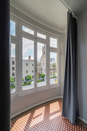 A room with a large window, a patterned floor, and a curtain. - Purple Nest Hostel (Valencia)