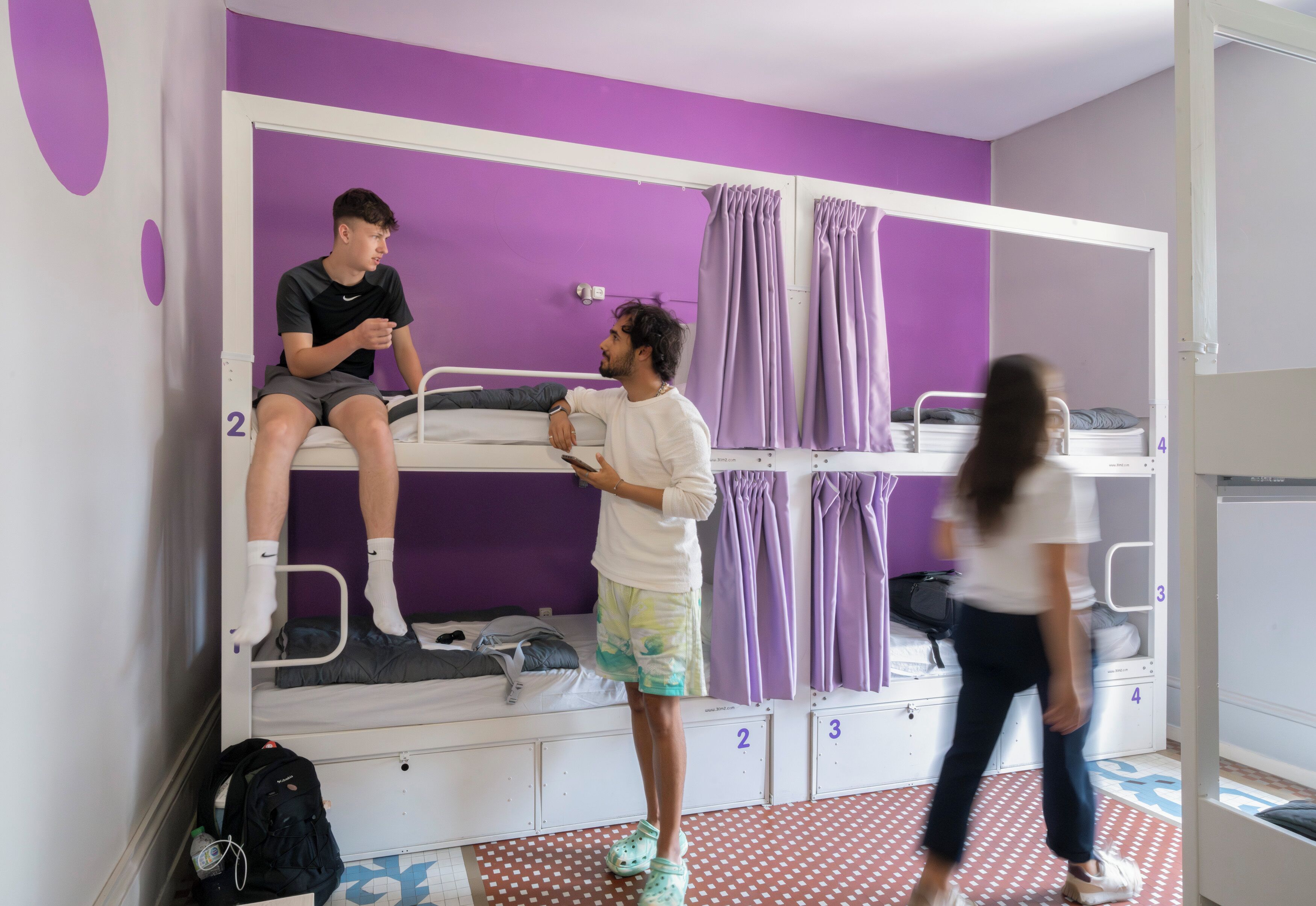 A bunk bed room with a purple wall, a white door, and numbered storage compartments.