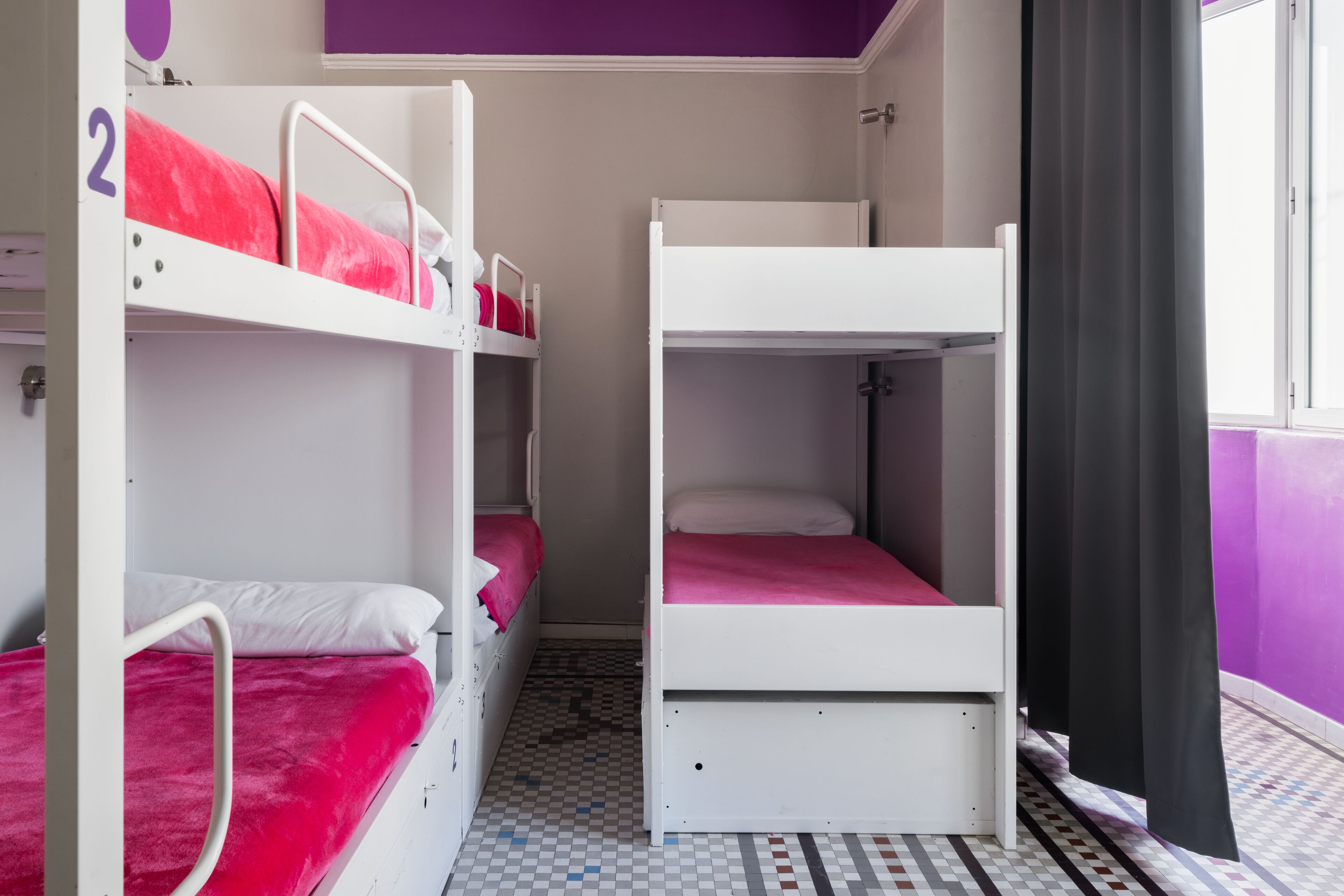 Un dormitorio con literas, piso a cuadros y una pared morada.