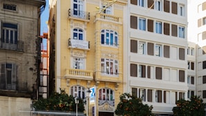 A multi-story building with a yellow facade, balconies, and a street view.