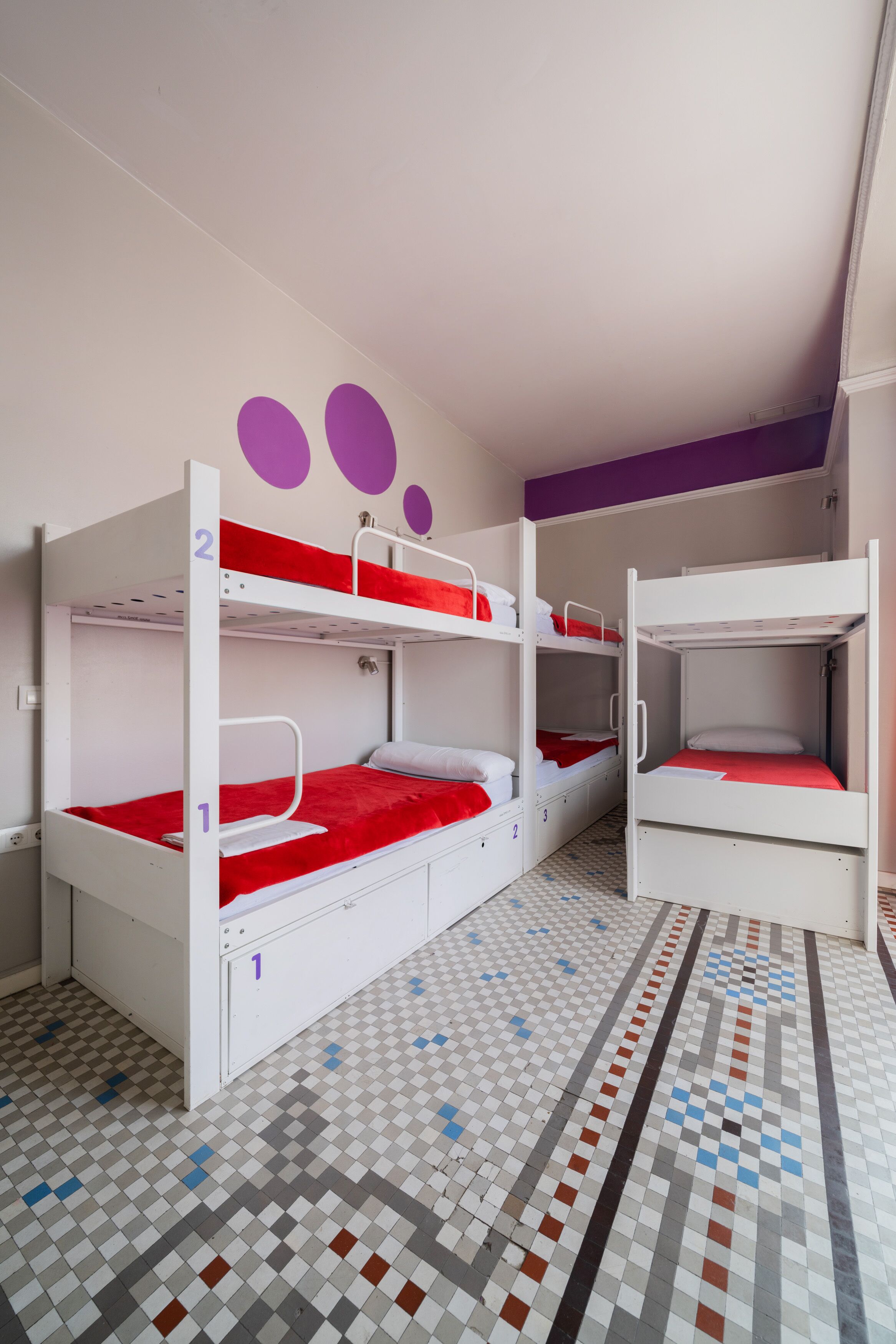 A room with bunk beds, a checkered floor, and a purple wall with circular decorations.
