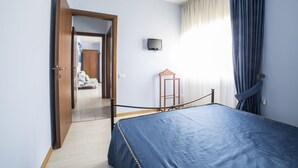 Une chambre à coucher avec un lit, un téléviseur fixé au mur et une porte donnant sur une autre pièce.