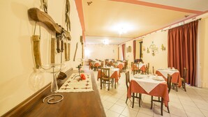 Un espace repas comprenant plusieurs tables et chaises, un banc en bois et des éléments de décoration fixés au mur.