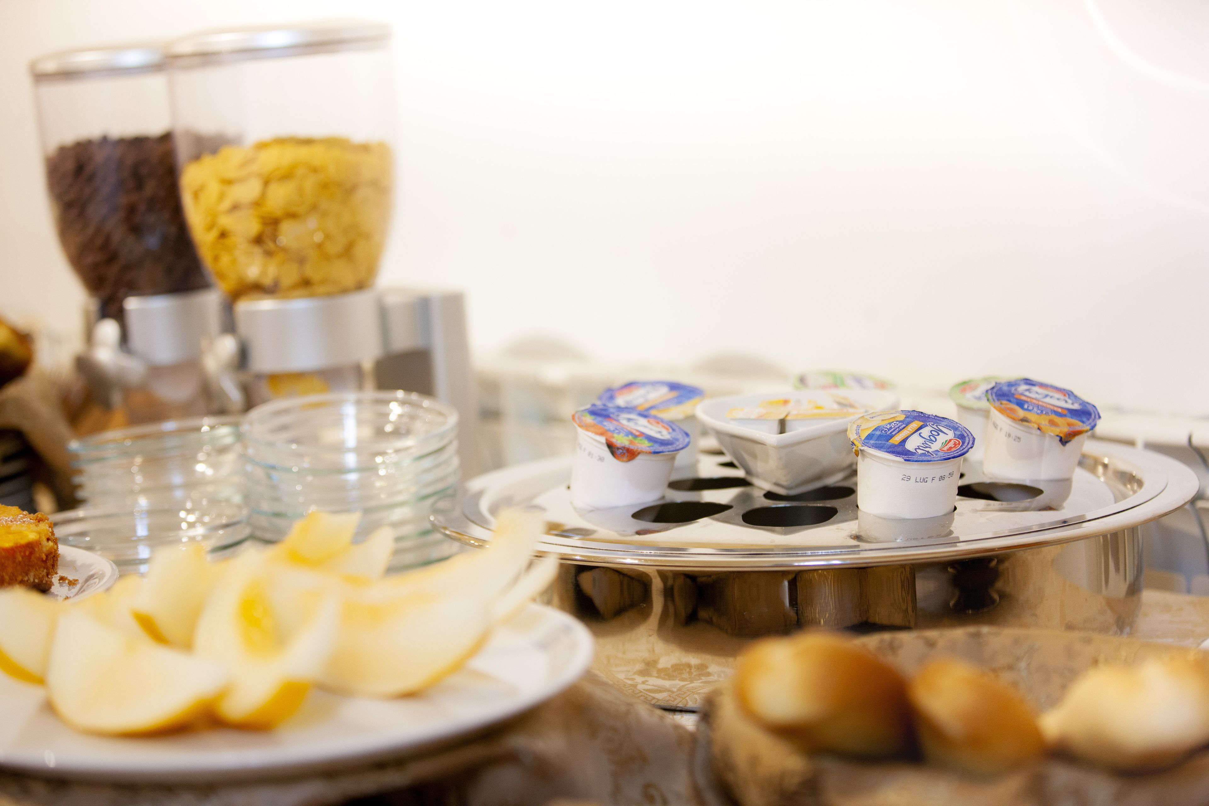 Une table de buffet proposant divers aliments, notamment des tranches de pommes, des pâtisseries et des pots de yaourt.