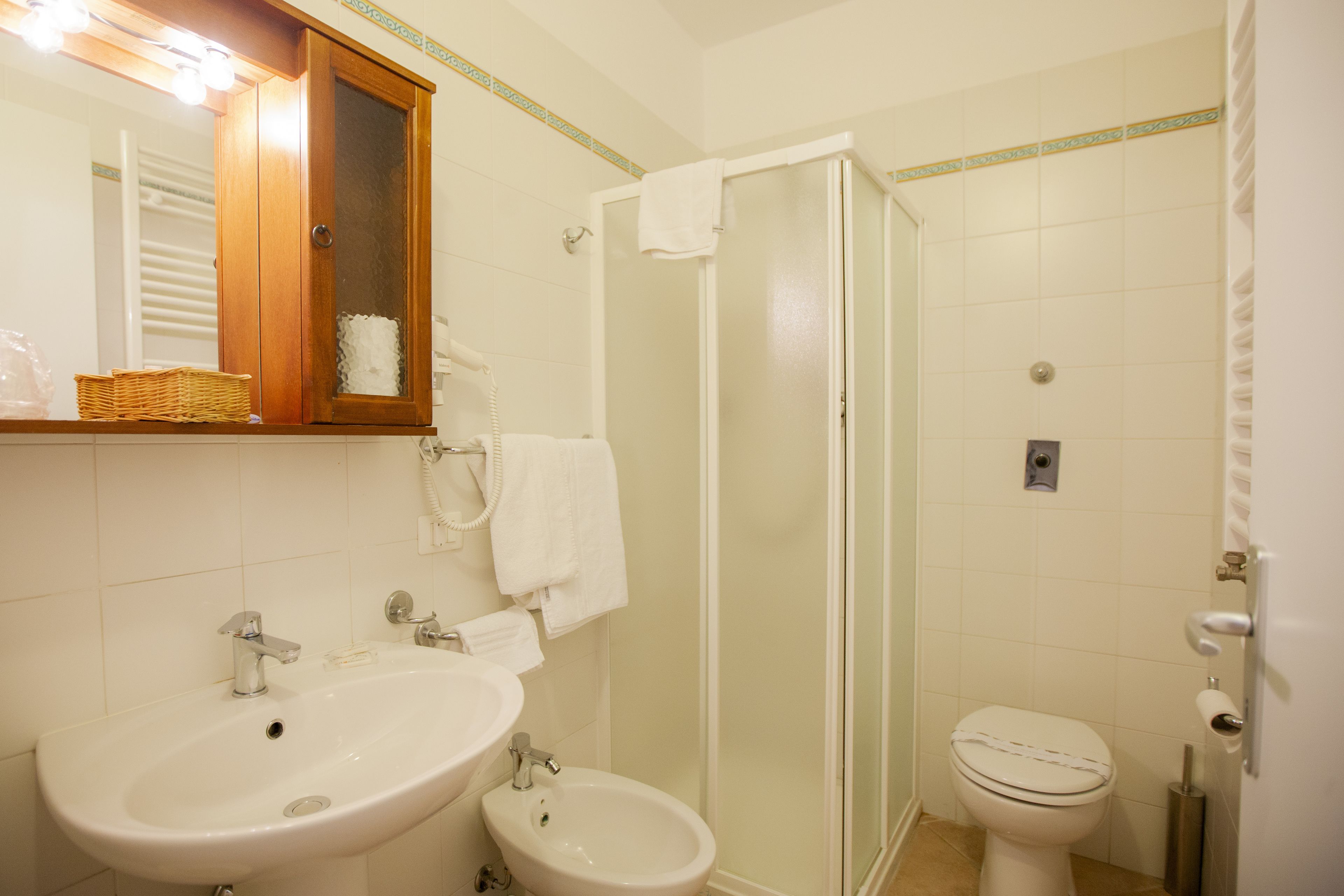 Un baño con lavamanos, bidé, inodoro y ducha con mampara de vidrio.