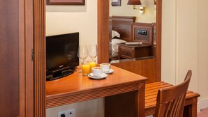 Een houten bureau met een televisie, twee wijnglazen, een beker en een schotel.