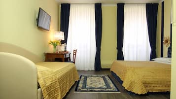 A hotel room with two beds, a desk with a chair, a TV mounted on the wall, and a window with curtains.