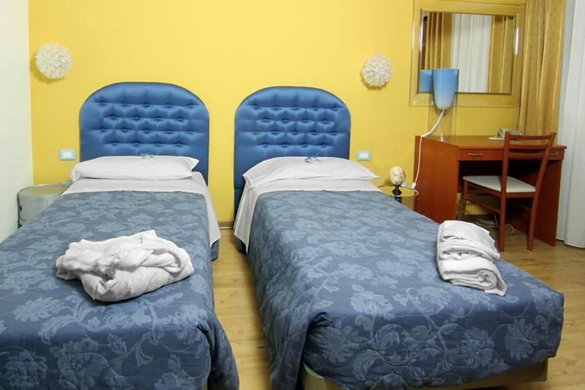 A double room with two beds, a desk, and a chair.