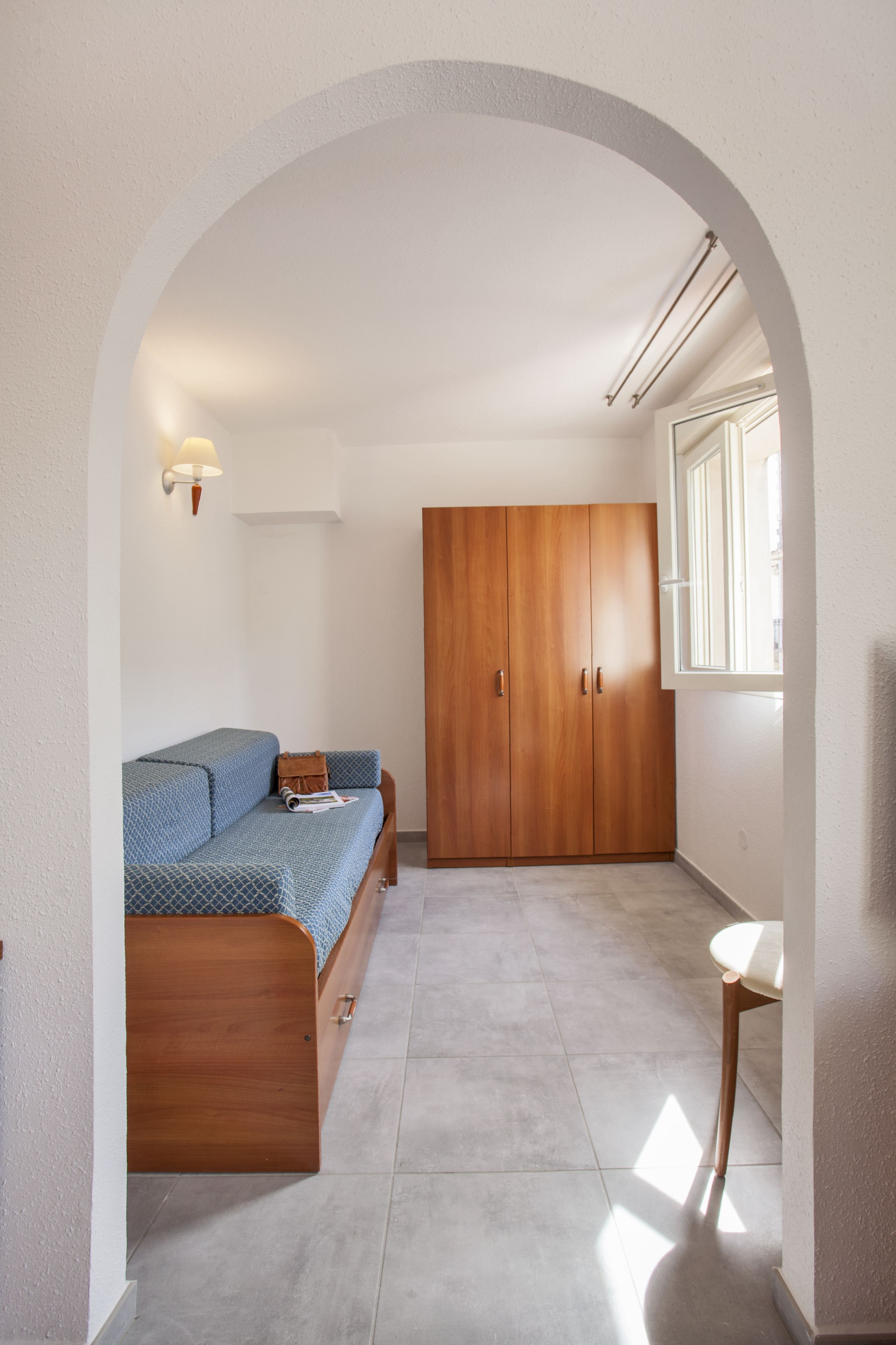 Un dormitorio con cama, armario y ventana.