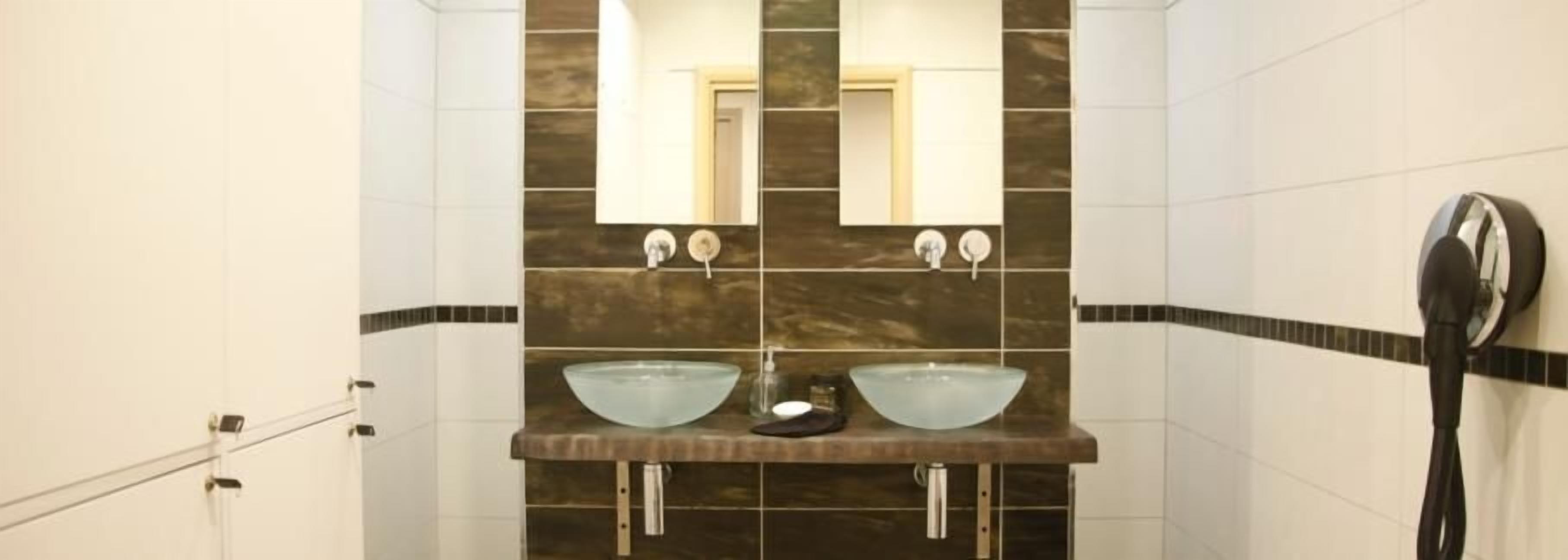 Une salle de bain avec deux lavabos, un miroir et un sèche-cheveux.