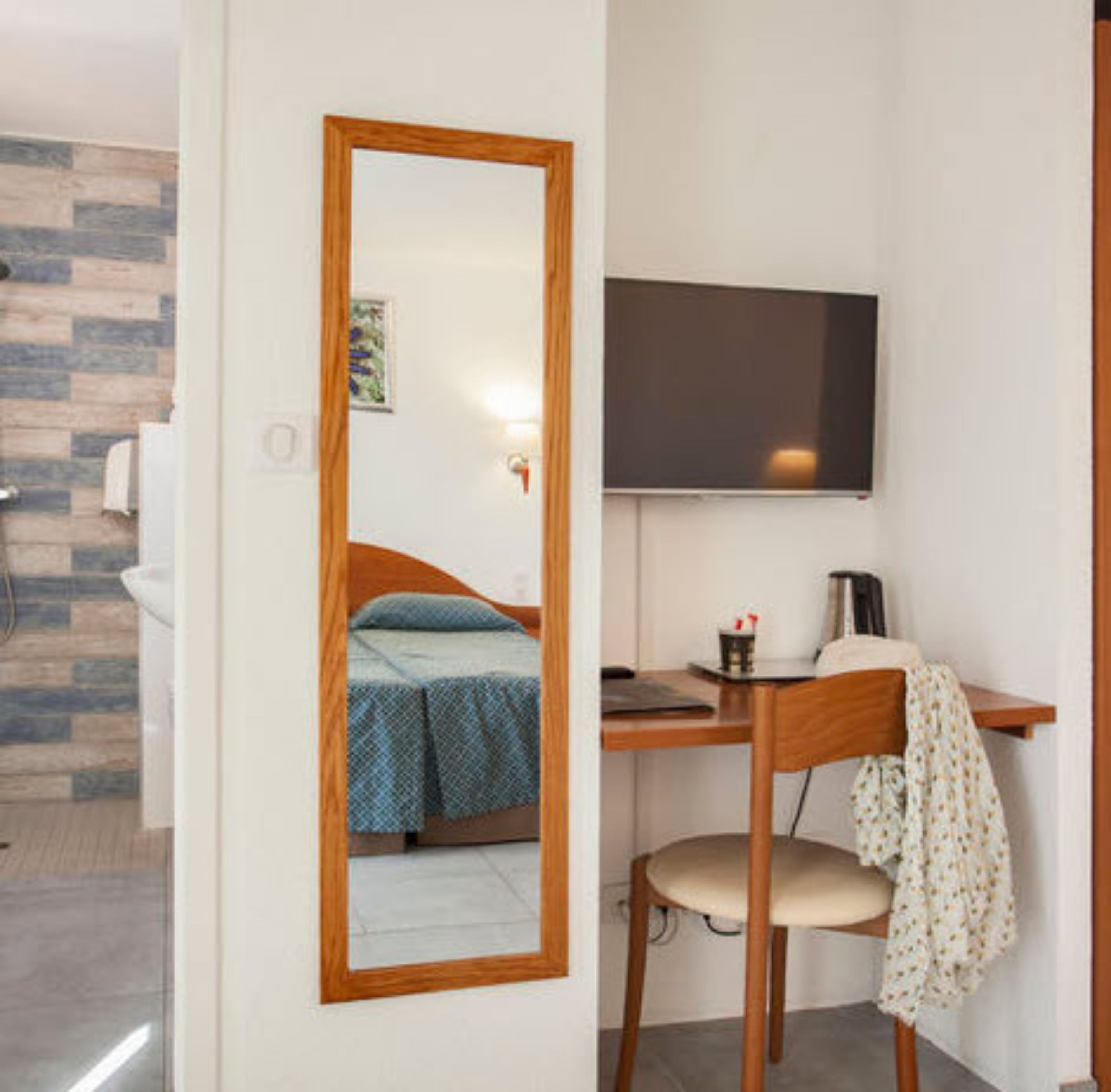 Un dormitorio pequeño con cama, escritorio, silla y televisor de pantalla plana.