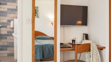 Un dormitorio pequeño con cama, escritorio, silla y televisor de pantalla plana.