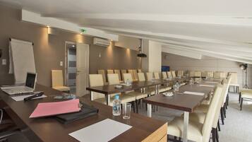 A conference room with long tables, chairs, a laptop, a water bottle, and a whiteboard.