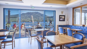 A restaurant with outdoor seating overlooking a lake and mountains. - Hôtel Le Neptune (Propriano)