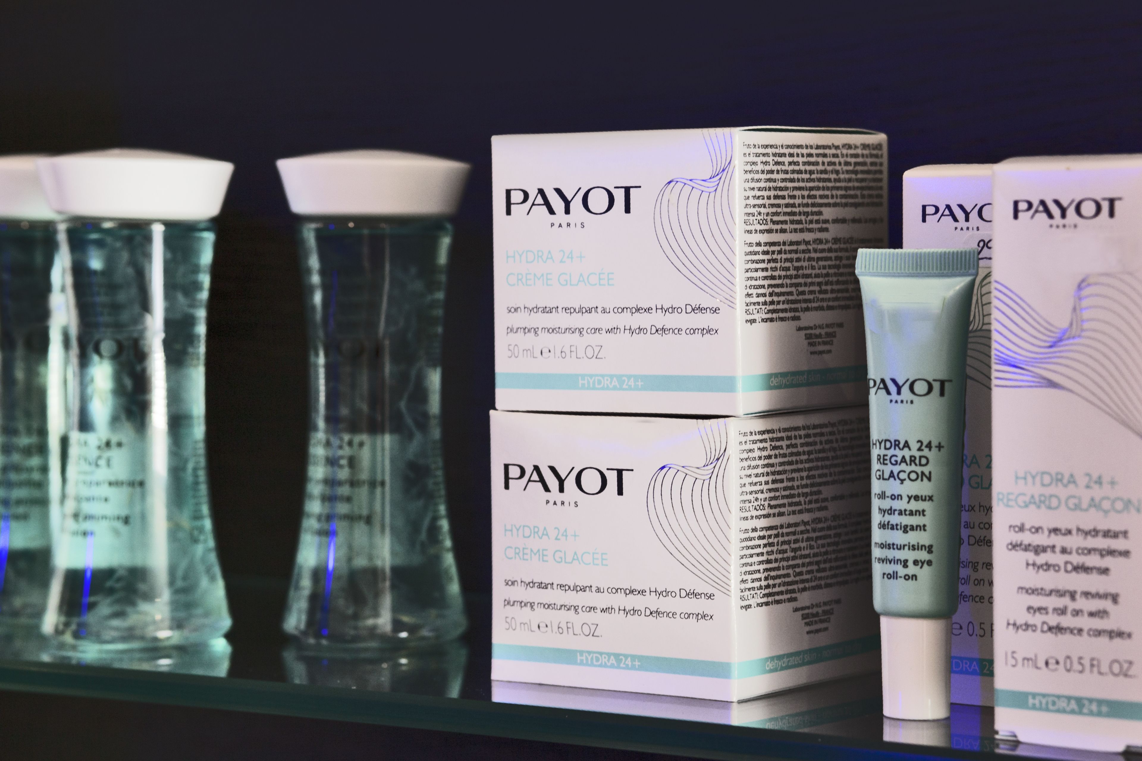 A display of PAYOT Paris Hydra 24+ Creme Glacee products, including a box, a tube, and two bottles.