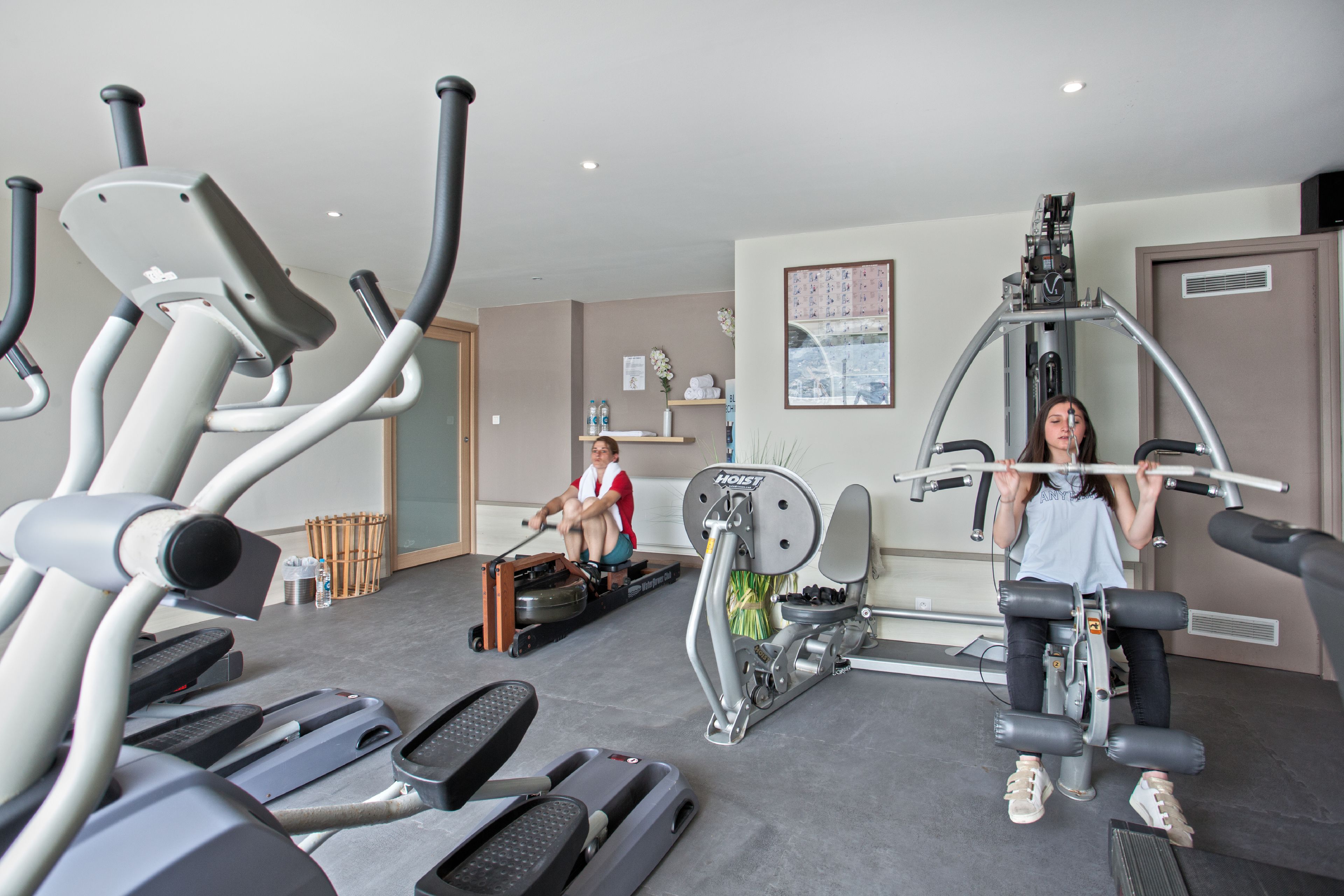 Een fitnessruimte met loopbanden, een roeimachine en een gewichtbank.