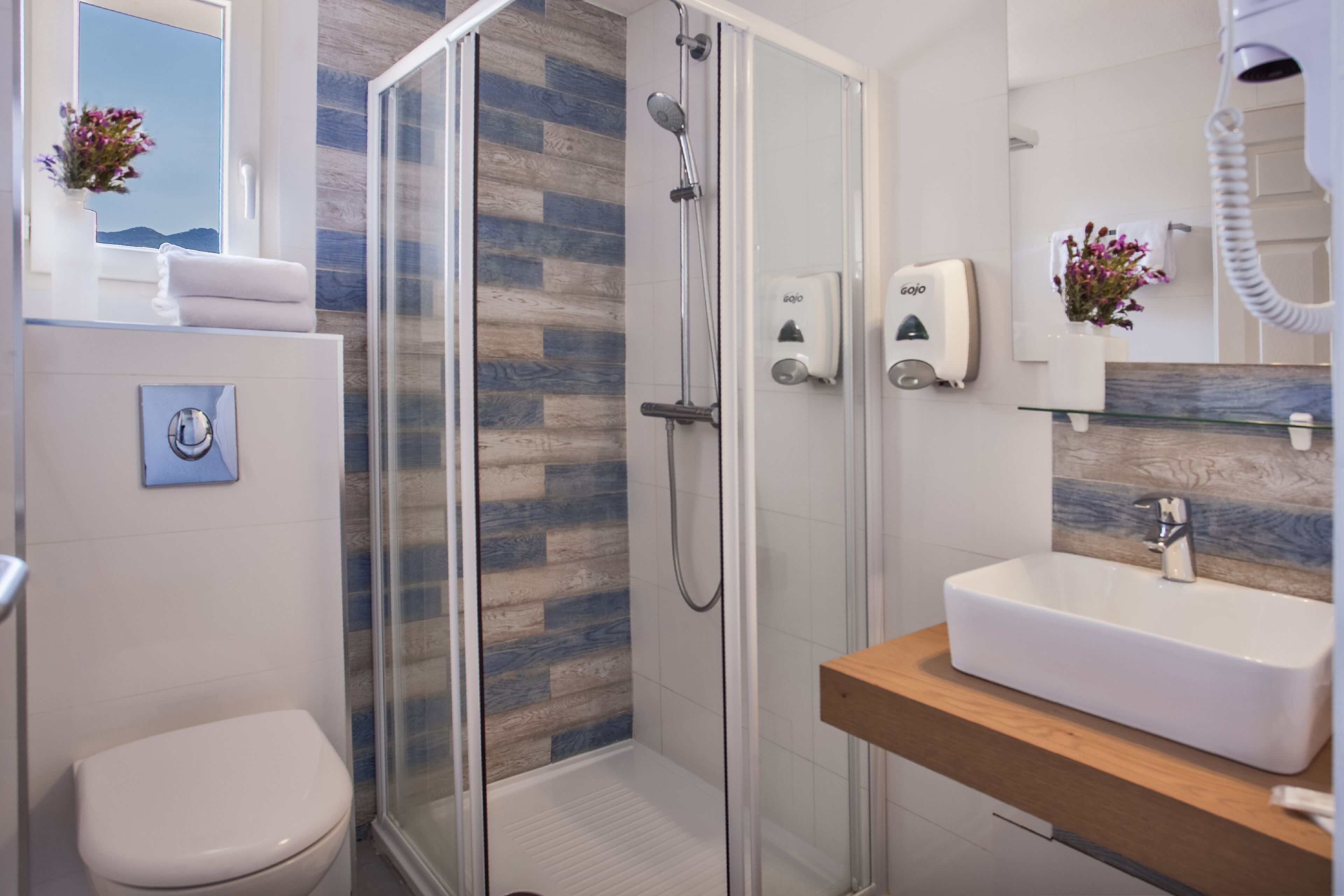 A modern bathroom with a glass-enclosed shower, a white sink, and a toilet.