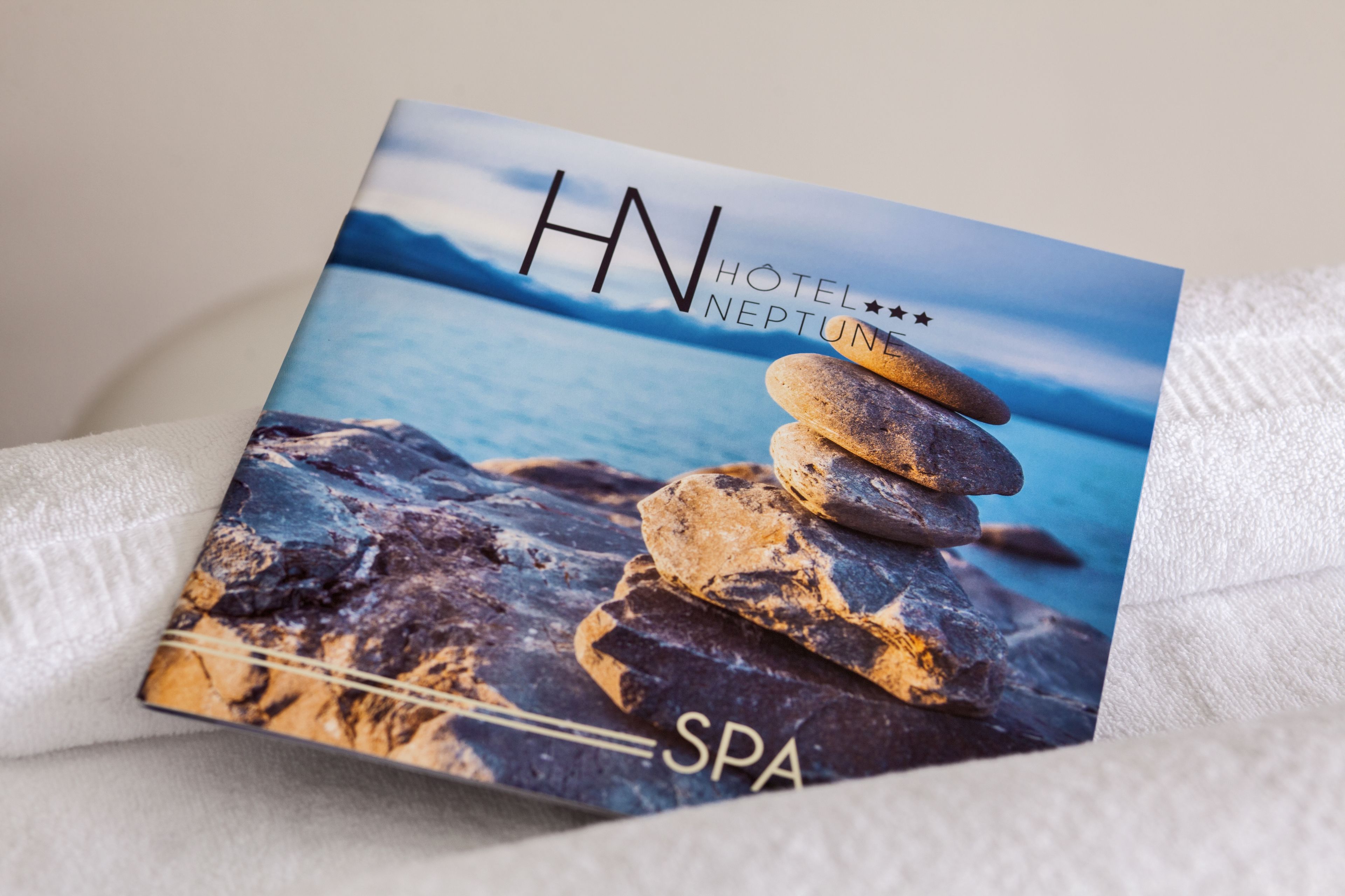 En broschyr för Hotel Neptune, med en hög stenar och utsikt över havet.
