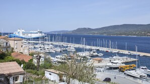 A marina with numerous boats docked, a large cruise ship in the background, and buildings surrounding the water. - Hôtel Le Neptune (Propriano)