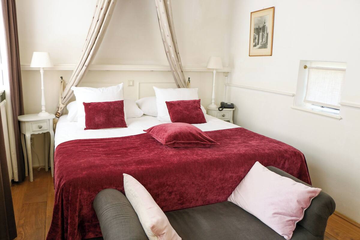 A neatly arranged bedroom with a bed, bedside tables, and a nightstand.