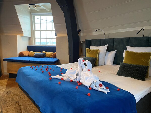 Une chambre avec un grand lit, un canapé bleu et une fenêtre donnant sur un beau paysage.