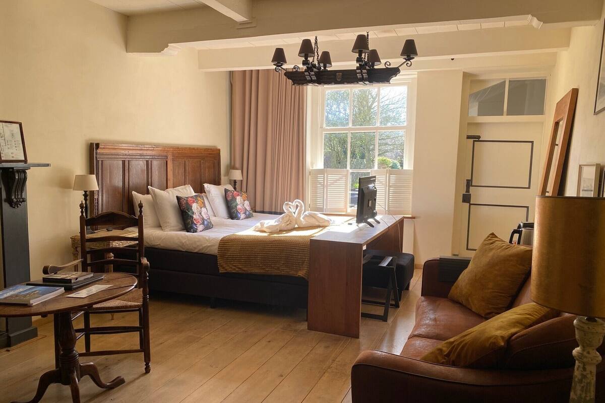 A cozy room with a bed, desk, and a brown leather sofa.