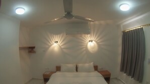 Een slaapkamer met een bed, twee nachtkastjes, een plafondventilator en twee wandlampen.