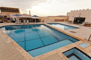 Alberca al aire libre, sombrillas en la alberca y camastros