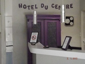 Un comptoir d’accueil d’hôtel avec une pancarte indiquant « HÔTEL DU CENTRE ».