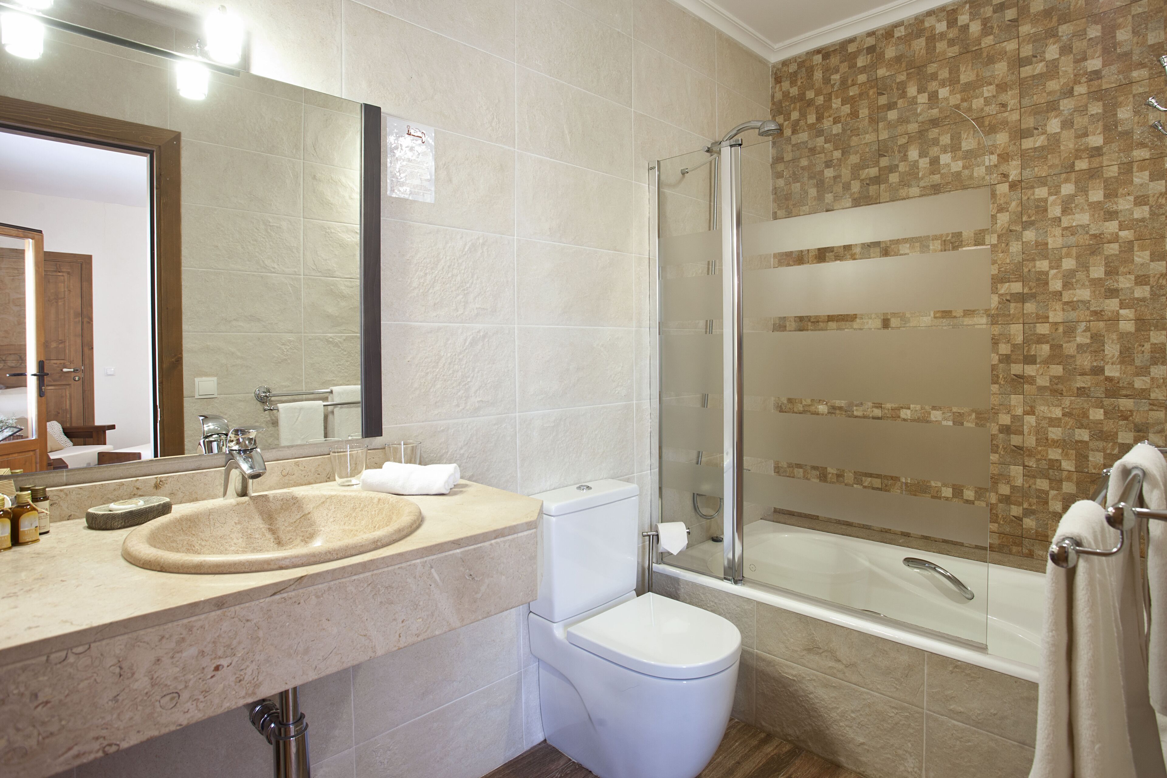 Un baño moderno con lavabo, inodoro y ducha con mampara de vidrio.