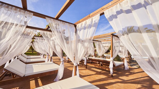 A sunlit outdoor lounge area with wooden pergolas and white canopies, providing shade and a view of the surrounding landscape. - Agroturismo Es Quatre Cantons (Binissalem)
