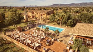 A resort with a pool, outdoor seating, and a view of the surrounding landscape. - Agroturismo Es Quatre Cantons (Binissalem)