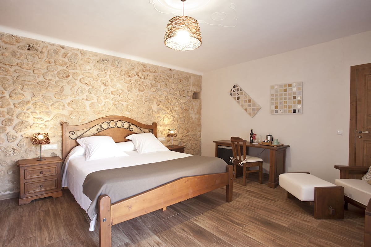 Ein Schlafzimmer mit Stehwänden, einem Holzbett, einem Schreibtisch und einem Stuhl.