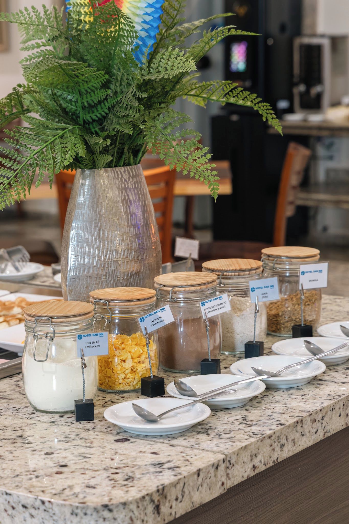 A buffet setup with various food items in glass jars and a decorative plant in a vase.