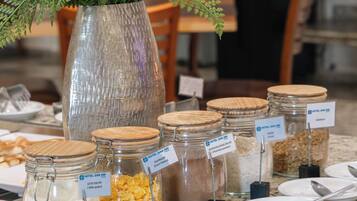 A buffet setup with various food items in glass jars and a decorative plant in a vase.