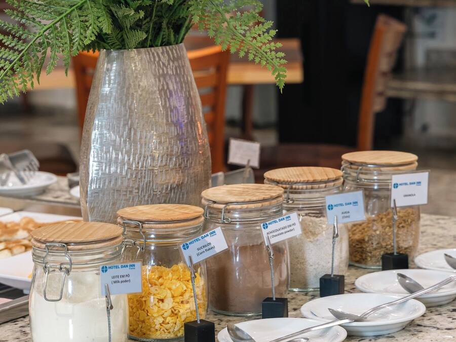 A buffet setup with various food items in glass jars and a decorative plant in a vase.