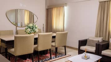 A modern living room with a dining table, chairs, a sofa, a coffee table, and a large mirror.