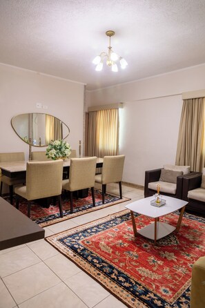 A modern living room with a dining table, chairs, a sofa, a coffee table, and a large mirror. - Dan Inn Franca by Nacional Inn (Franca)