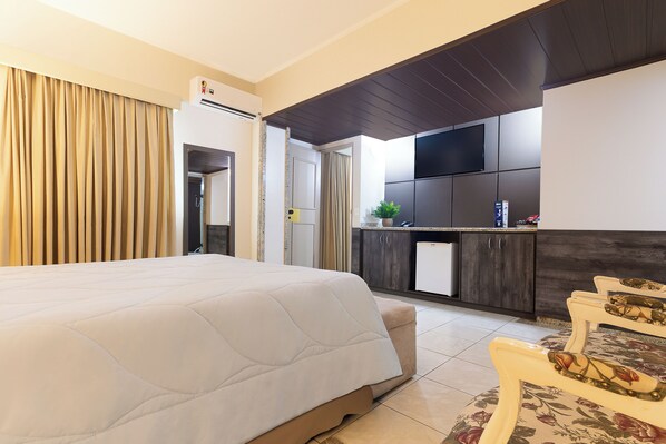 A hotel room with a large bed, a small kitchenette, and a dining area with chairs. - Dan Inn Franca by Nacional Inn (Franca)