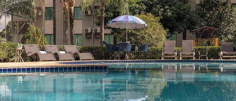 A swimming pool with lounge chairs and an umbrella.