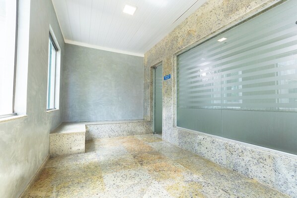 A hallway with a speckled floor, a door with frosted glass, and a sign on the wall.