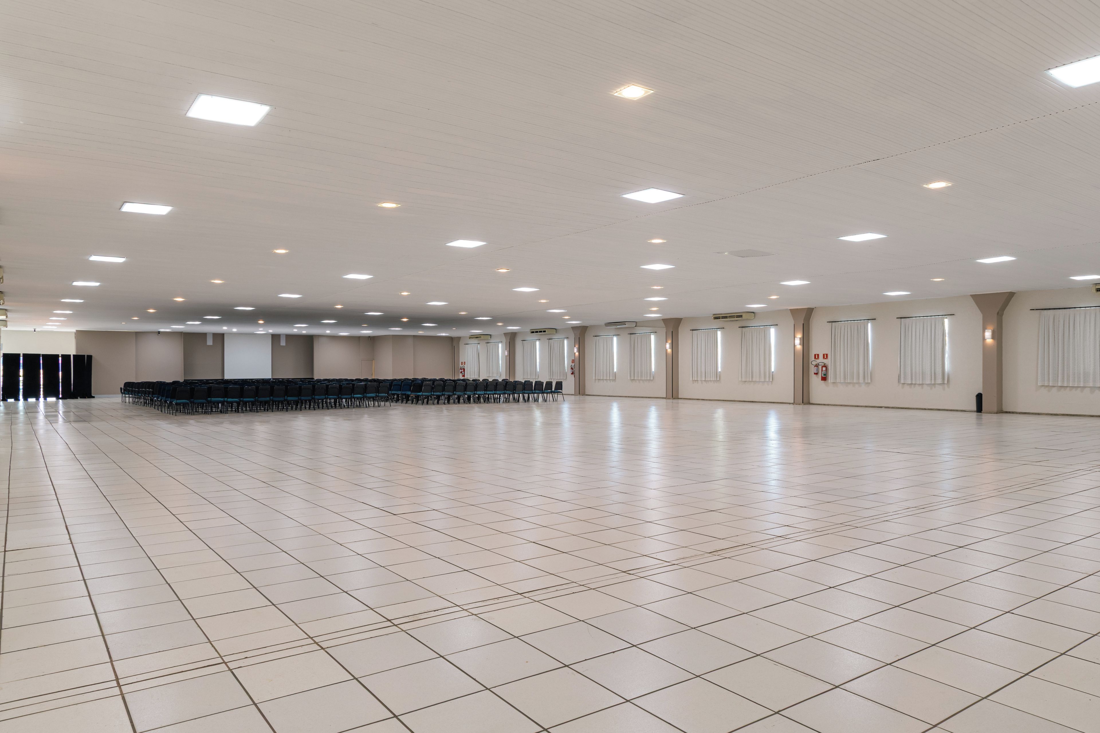 A spacious hall with a tiled floor, rows of chairs, and ceiling lights.