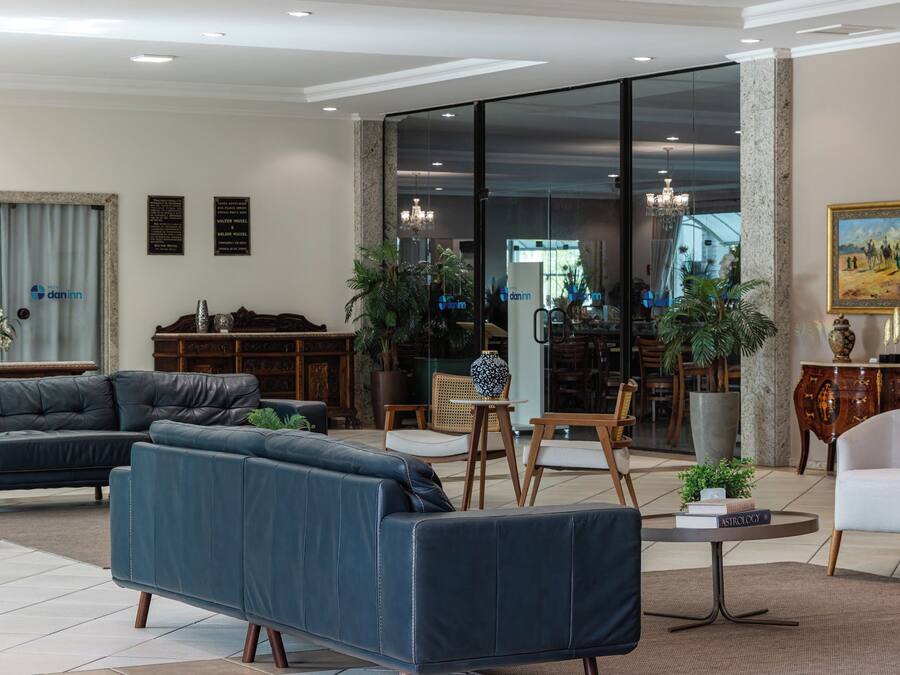 Ein modernes Wohnzimmer mit Ledersofas, einem Essbereich und einer großen Glasdoor, die auf einen Balkon führt.