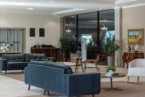 A modern living room with leather sofas, a dining area, and a large glass door leading to a balcony. - Dan Inn Franca by Nacional Inn (Franca)