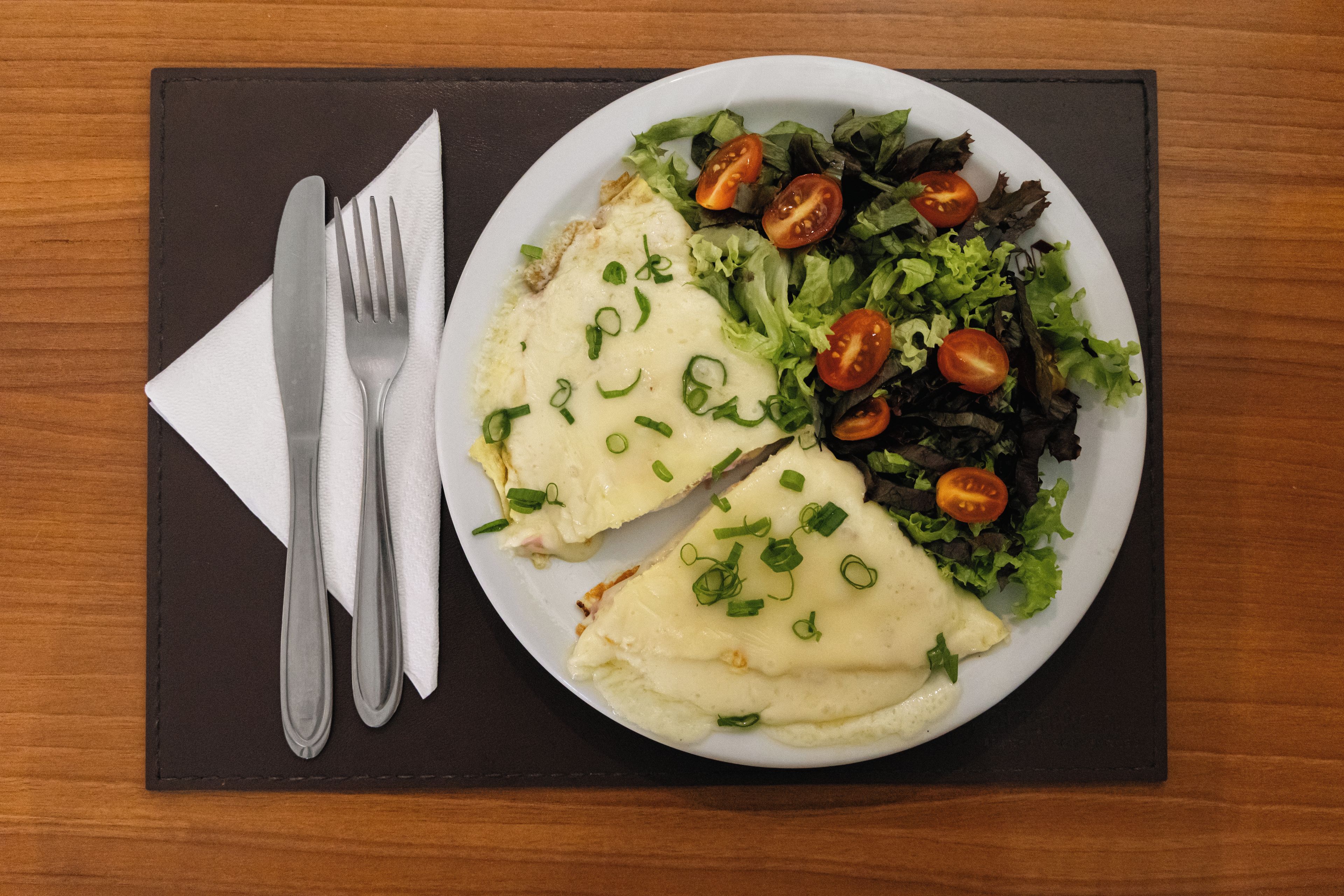 A plate of food with a fork and knife on a dark placemat.