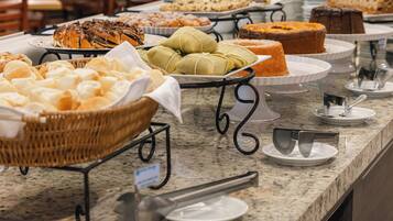 Buffet com diversos pães e doces.