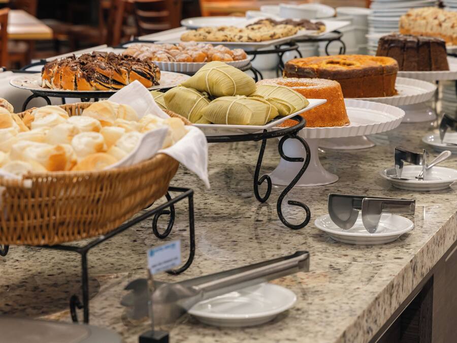 Buffet com diversos pães e doces.