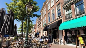 Een straat met terrasjes, fietsen en diverse winkels.